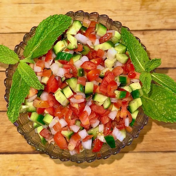 Afghan salad with diced tomatoes, cucumbers, and onions, garnished with fresh mint leaves.