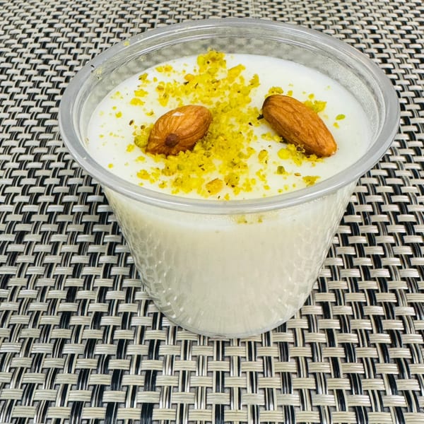 Afghan dessert Firni, a creamy pudding topped with ground pistachios and two whole almonds.