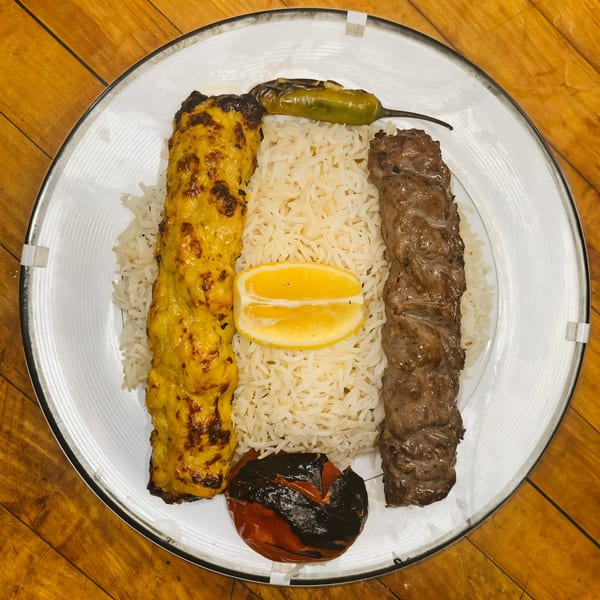 Afghan Kabob House's chicken and beef kabobs with rice, lemon, grilled tomato, and pepper.